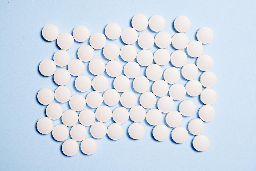 Viele weiße Tabletten auf einem Foto, Symbolbild für Medikamentenübergebrauchskopfschmerzen