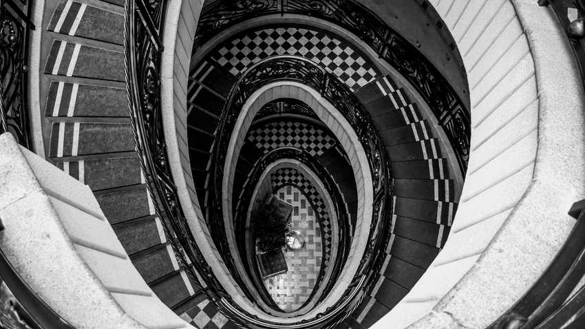 Wendeltreppe in Grau-Schwarz von oben fotografiert, spiralförmig, Symbolbild für Schwindel und vestibuläre Migräne